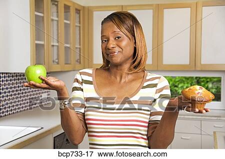 African woman holding apple and muffin View Large Photo Image Stock Photo - African woman holding apple and muffin. Fotosearch