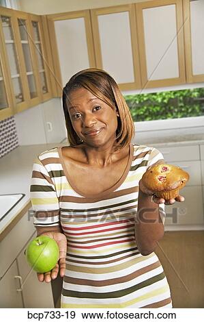 African woman holding apple and muffin View Large Photo Image Stock Photo - African woman holding apple and muffin. Fotosearch