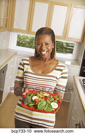 African woman holding plate of vegetables View Large Photo Image Stock Image - African woman holding plate of vegetables. Fotosearch