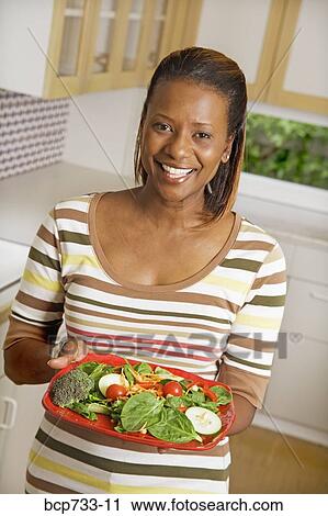 African woman holding plate of vegetables View Large Photo Image Stock Image - African woman holding plate of vegetables. Fotosearch
