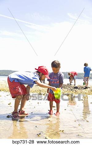 Stock Photo - Asian sister and brother playing at beach. Fotosearch