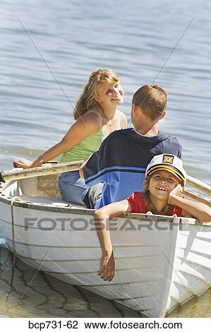 Stock Image - Boy and girl in row boat with young sibling. Fotosearch