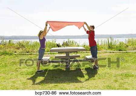 Stock Photograph - Boy and girl placing table cloth on picnic table. Fotosearch