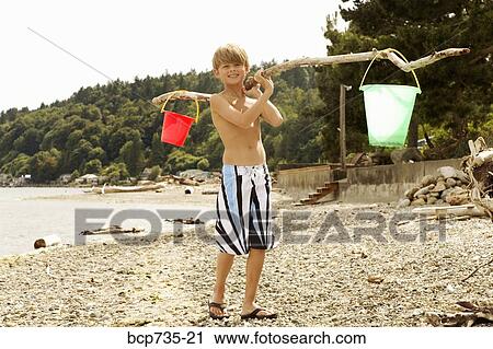 Boy carrying buckets at beach View Large Photo Image Stock Image - Boy carrying buckets at beach. Fotosearch