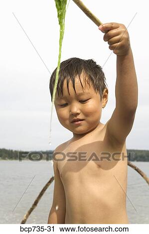 Stock Image - Boy holding stick with seaweed. Fotosearch
