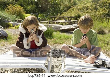 Brother and sister looking at cell phones View Large Photo Image Stock Image - Brother and sister looking at cell phones. Fotosearch