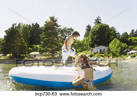 Stock Image - Brother and sister playing on raft. Fotosearch