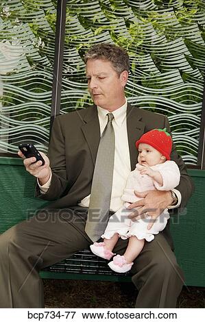 Businessman holding baby at bus stop View Large Photo Image Stock Photo - Businessman holding baby at bus stop. Fotosearch