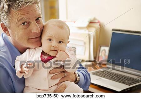Stock Image - Businessman holding baby. Fotosearch
