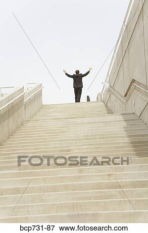 Businessman with arms raised at top of steps View Large Photo Image Stock Photo - Businessman with arms raised at top of steps. Fotosearch