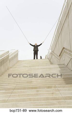 Businessman with arms raised at top of steps View Large Photo Image Stock Photo - Businessman with arms raised at top of steps. Fotosearch