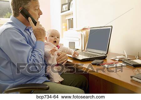 Picture - Businessman working with baby on lap. Fotosearch