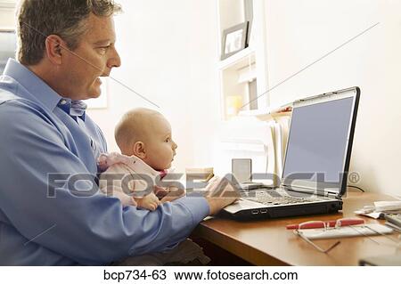 Stock Image - Businessman working with baby on lap. Fotosearch