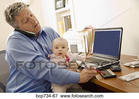 Stock Photo - Businessman working with baby on lap. Fotosearch