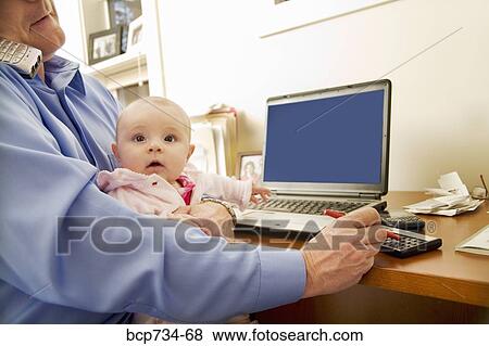 Businessman working with baby on lap View Large Photo Image Stock Photo - Businessman working with baby on lap. Fotosearch