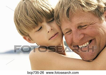 Close up of father and son hugging View Large Photo Image Stock Photograph - Close up of father and son hugging. Fotosearch