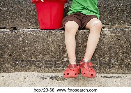 Stock Photo - Close up of young boy sitting on steps. Fotosearch