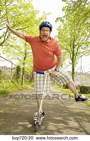 Stock Image - Clumsy man riding a scooter. Fotosearch