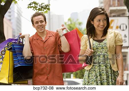 Couple carrying shopping bags View Large Photo Image Stock Photo - Couple carrying shopping bags. Fotosearch