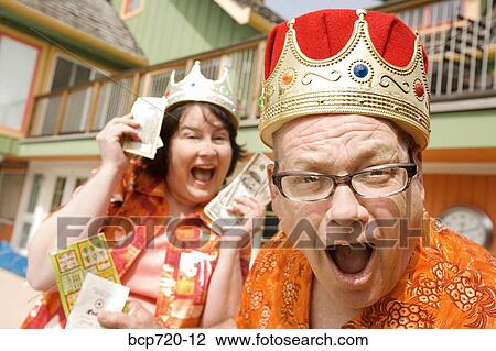 Stock Image - Couple in festive outfits and crowns. Fotosearch