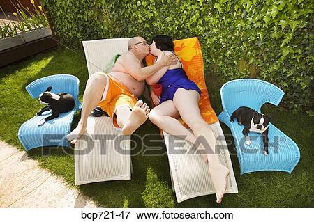 Couple kissing on lawn chairs in backyard View Large Photo Image Stock Photo - Couple kissing on lawn chairs in backyard. Fotosearch