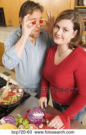 Stock Image - Couple playing with food while cooking. Fotosearch