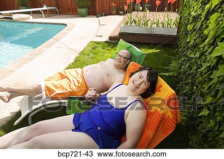 Couple relaxing on lawn chairs in backyard View Large Photo Image Stock Image - Couple relaxing on lawn chairs in backyard. Fotosearch