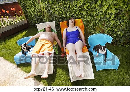 Couple relaxing on lawn chairs in backyard View Large Photo Image Stock Photograph - Couple relaxing on lawn chairs in backyard. Fotosearch