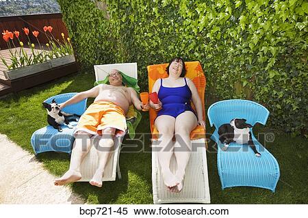 Couple relaxing on lawn chairs in backyard View Large Photo Image Stock Photography - Couple relaxing on lawn chairs in backyard. Fotosearch