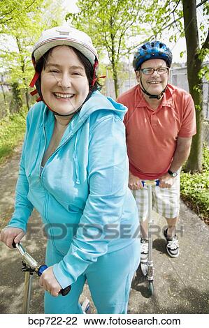 Stock Image - Couple riding scooters together. Fotosearch