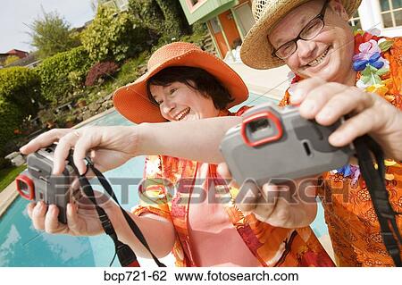 Stock Image - Couple wearing festive outfits taking self portraits. Fotosearch