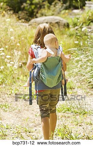 Girl carrying baby sibling on back View Large Photo Image Stock Image - Girl carrying baby sibling on back. Fotosearch