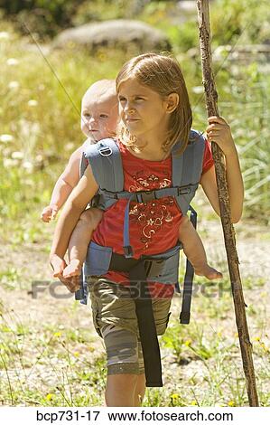 Girl carrying baby sibling on back View Large Photo Image Stock Photo - Girl carrying baby sibling on back. Fotosearch