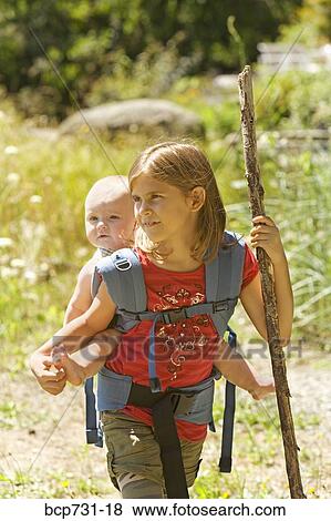 Stock Photo - Girl carrying baby sibling on back. Fotosearch