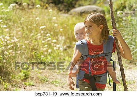 Girl carrying baby sibling on back View Large Photo Image Stock Photo - Girl carrying baby sibling on back. Fotosearch