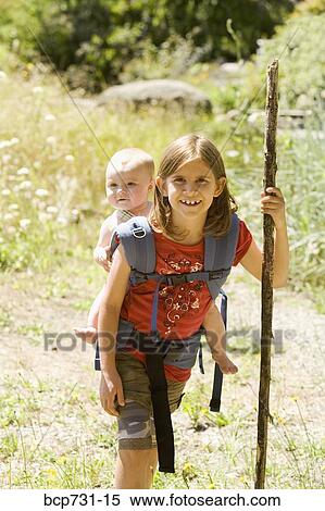 Stock Photography - Girl carrying baby sibling on back. Fotosearch