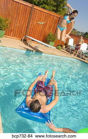 Girl jumping over father into swimming pool View Large Photo Image Picture - Girl jumping over father into swimming pool. Fotosearch