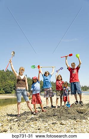 Stock Image - Group of children cheering at beach. Fotosearch