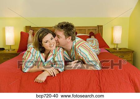Stock Image - Kissing couple wearing matching pajamas. Fotosearch