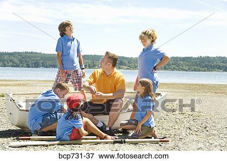 Stock Photo - Male camp counselor and children at beach. Fotosearch