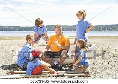 Stock Photography - Male camp counselor and children at beach. Fotosearch