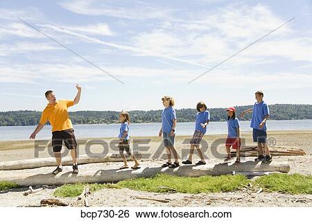 Stock Photograph - Male camp counselor with children at beach. Fotosearch