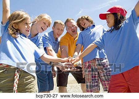 Stock Photo - Male camp counselor with children in huddle. Fotosearch