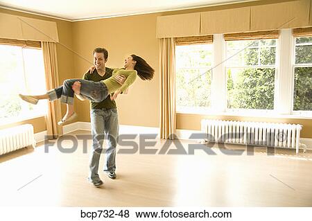 Man carrying wife in new house View Large Photo Image Stock Photo - Man carrying wife in new house. Fotosearch