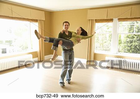 Man carrying wife in new house View Large Photo Image Stock Photo - Man carrying wife in new house. Fotosearch