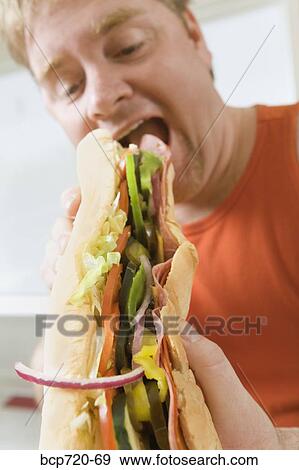Man eating a big hoagie sandwich View Large Photo Image Stock Photo - Man eating a big hoagie sandwich. Fotosearch