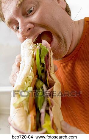Picture - Man eating a sandwich. Fotosearch