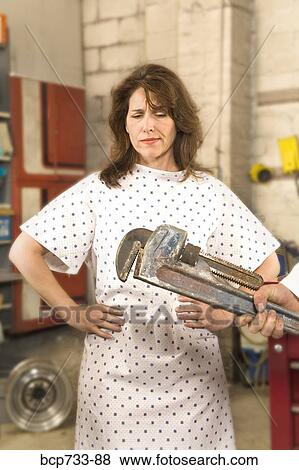 Man holding wrench in front of woman in hospital gown View Large Photo Image Stock Photo - Man holding wrench in front of woman in hospital gown. Fotosearch