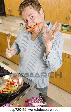 Stock Photo - Man playing with food while cooking. Fotosearch