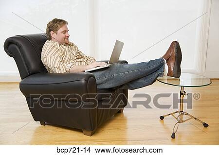 Man using a laptop in armchair View Large Photo Image Picture - Man using a laptop in armchair. Fotosearch